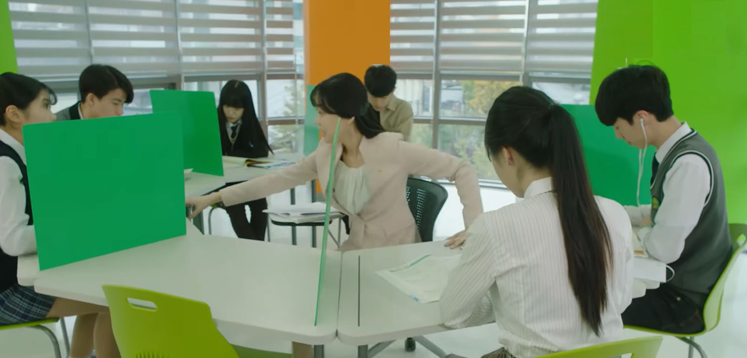 선생님을 가운데 두고 학생들이 원형 테이블에 둘러앉아 공부하는 모습